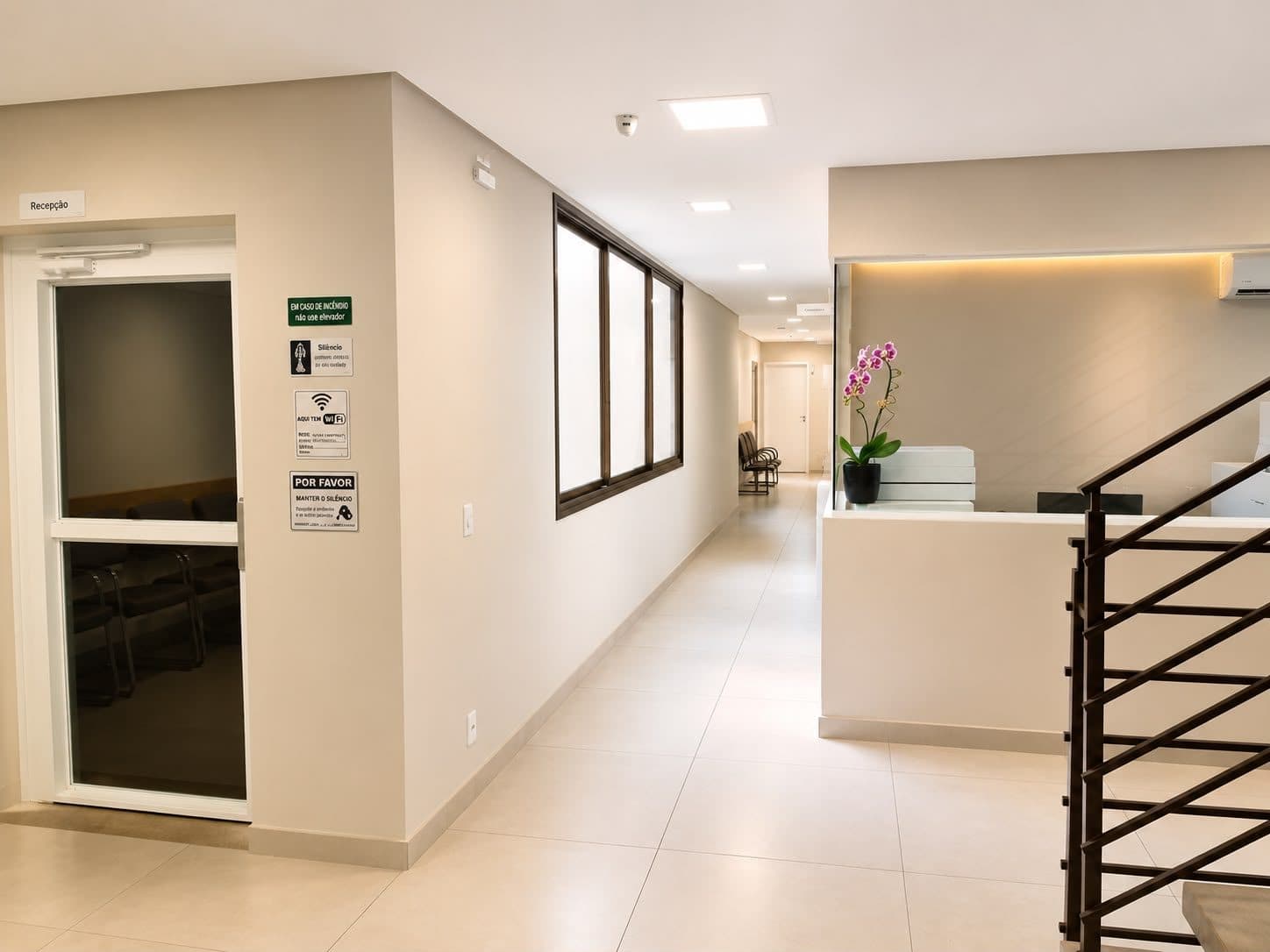 Corredor de acesso aos consultórios da Nova Campinas Oftalmologia, com balcão de apoio e sinalização da recepção